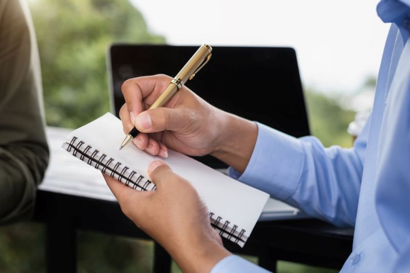 Male hands taking notes on a handwritten notepad, creative writing.