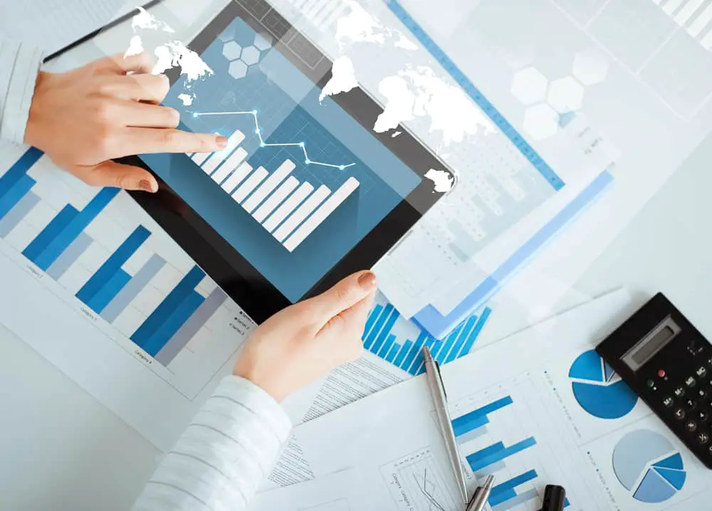 Person looking at charts on a tablet and documents on table