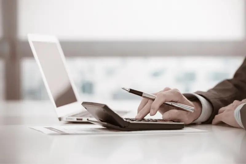 Person using calculator in front of the laptop