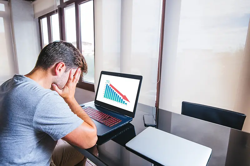 Young man at office lamenting with hands on the head in front of computer
