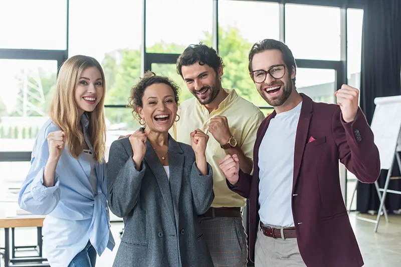 Excited interracial business people showing yes gesture at camera in office
