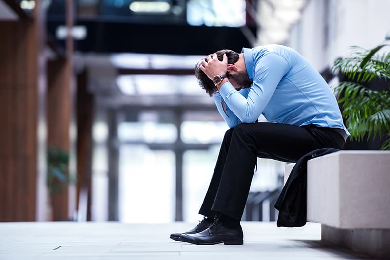 Is stress affecting you at work? Frustrated young business man working on laptop computer at office