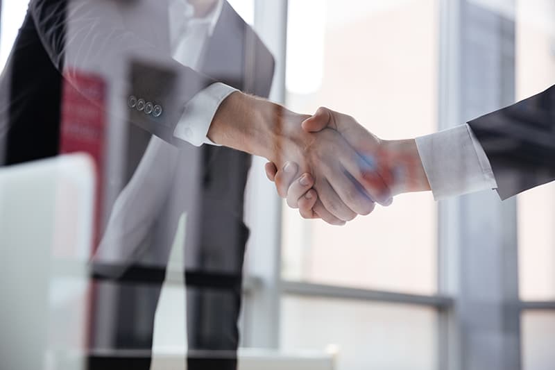 Closeup of two businessmen standing and shaking hands in office
