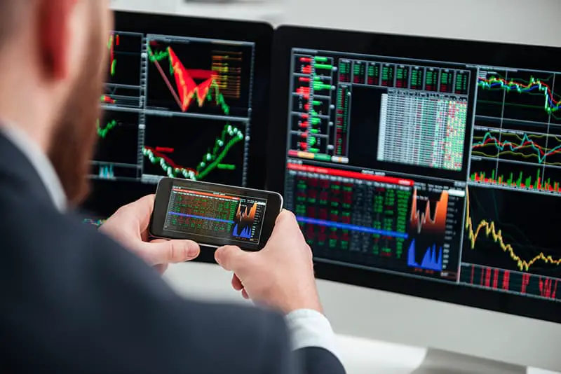 Back view of businessman sitting and working with computer and smartphone in office