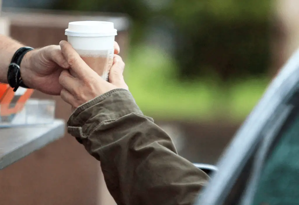 Someone handing over a hot drink to customer in drive through take away