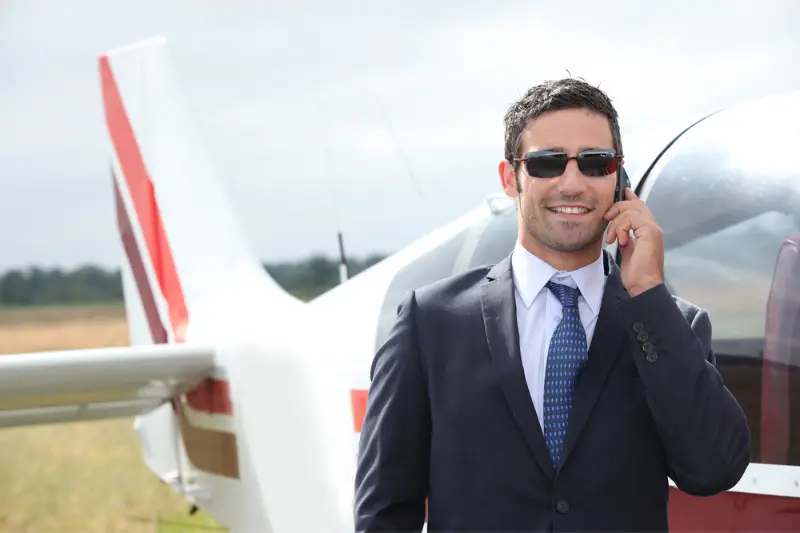 Man talking on a mobile phone next to a private plane