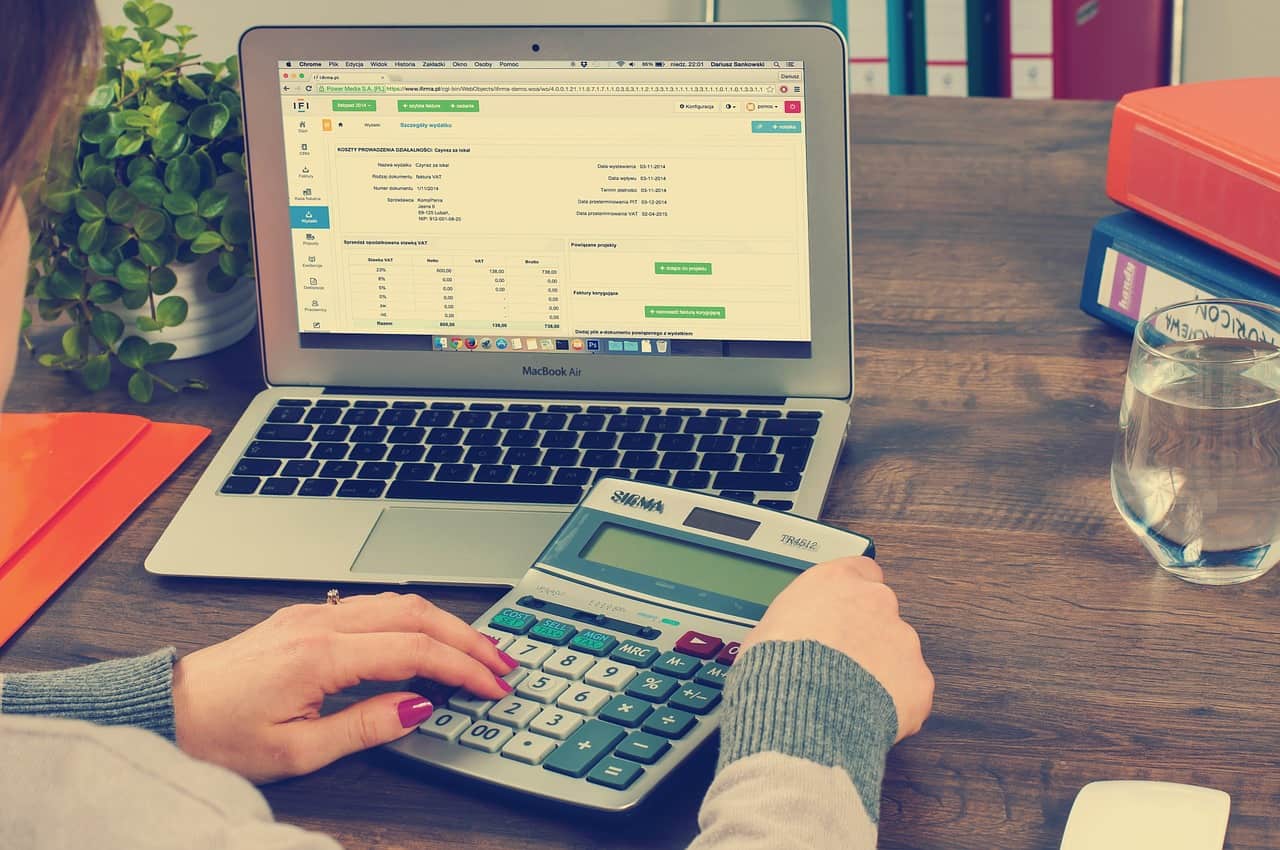 person using a calculator next to a laptop.