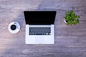 clear desk - get rid of clutter - laptop coffee cup and plant