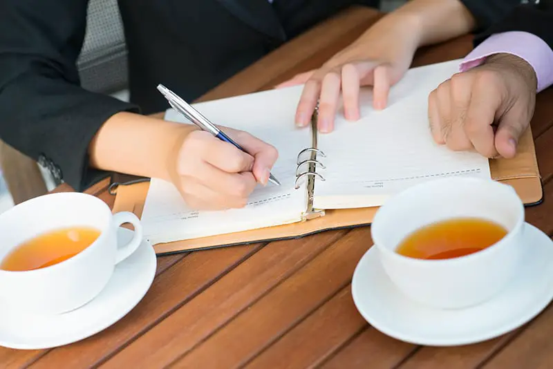 Close-up of colleagues planning their daily business activity over tea