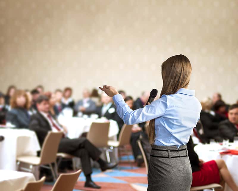 Beautiful business woman is speaking on conference.