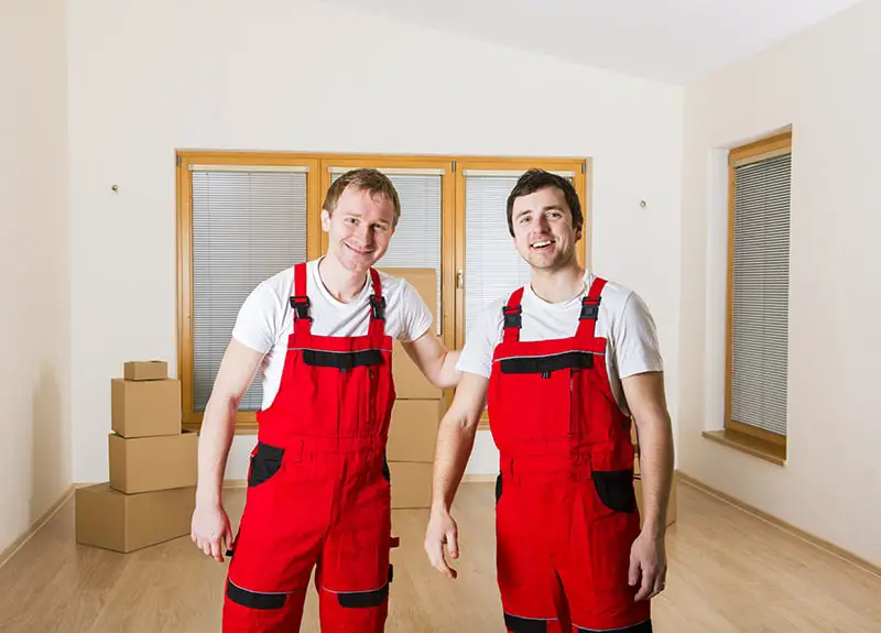 Movers in new house with lot of boxes behind them.