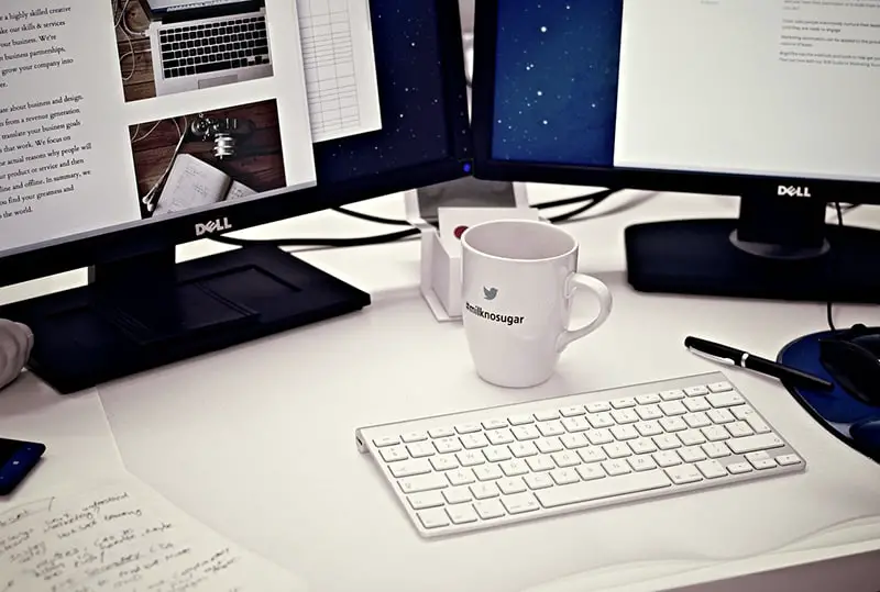  monitors showing ideas for businesses - next to keyboard and mug on desk