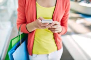 Female customer with cellular phone and shopping bags in the mall - customers