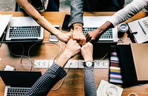 group hand fist bump across a desk