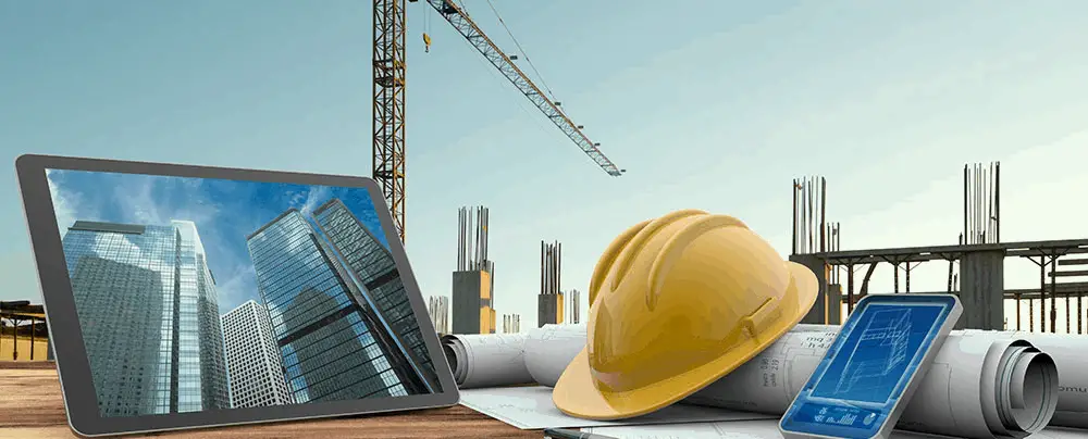 Hardhat blueprint mobile and tablet on wooden surface with construction site background