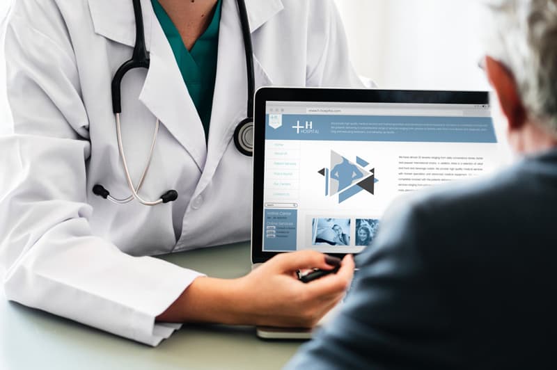 doctor pointing at laptop screen showing it to patient