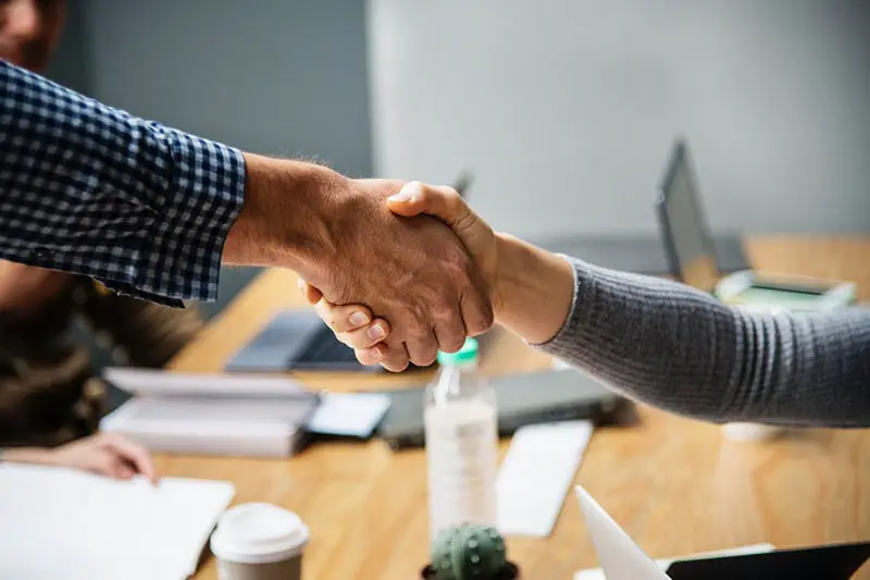 Two people shaking hands over a table