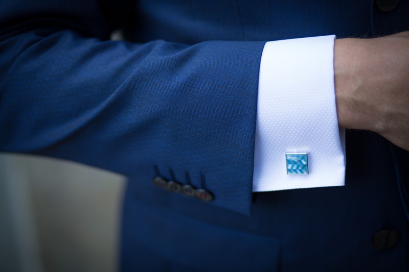 person wearing blue suit and white shirt with cufflinks