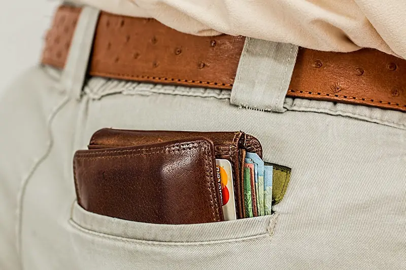 Close up of wallet containing cash and card in back trouser pocket