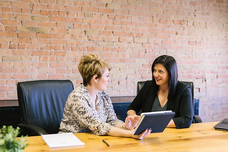 Two women having a discussion, one holding a tablet