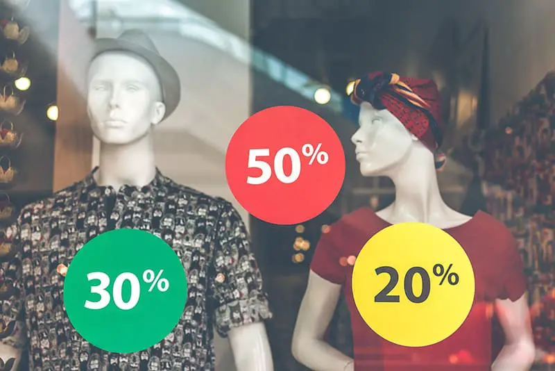 Male and female mannequin in shop window with sale stickers