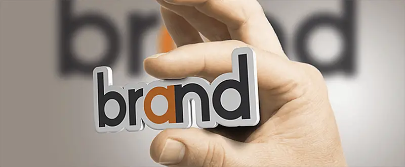 person holding the word brand between fingers