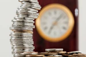 Pile of coins, currency, investment , clock in background