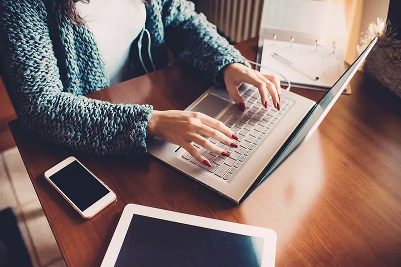 Close up on the hands of young woman using computer, tablet and smart phone - business, technology, multitasking concept