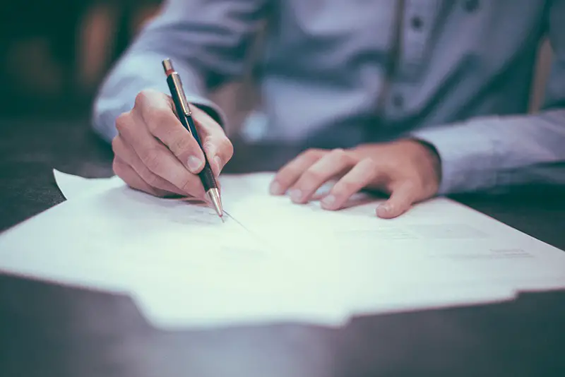 man signing documents on desk