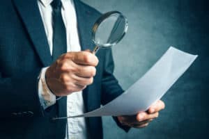 Man looking at document through a magnifying glass