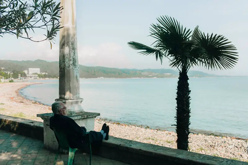 man sitting on chair next to the beach ooking out to sea