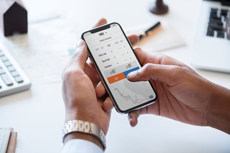 Man holding silver iPhone showing FOREX data