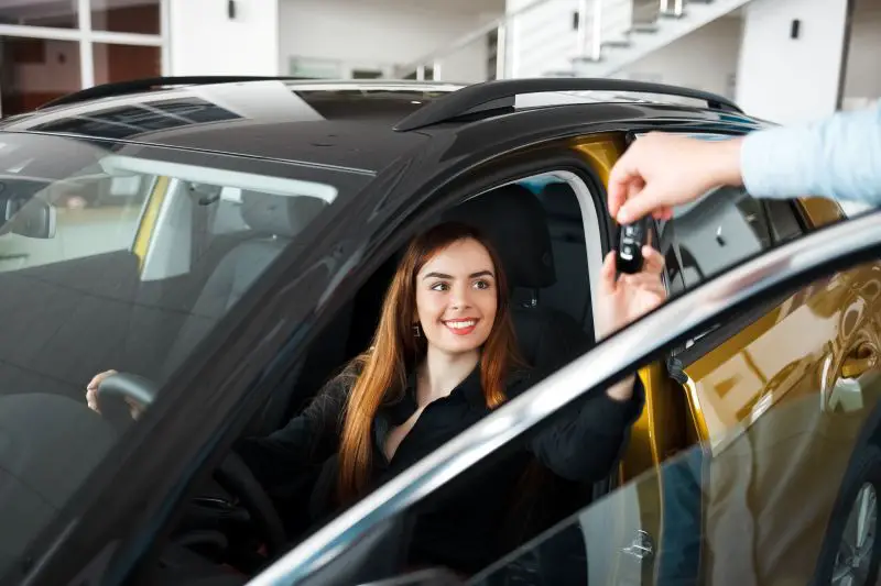 Car dealership seller gives client a car key