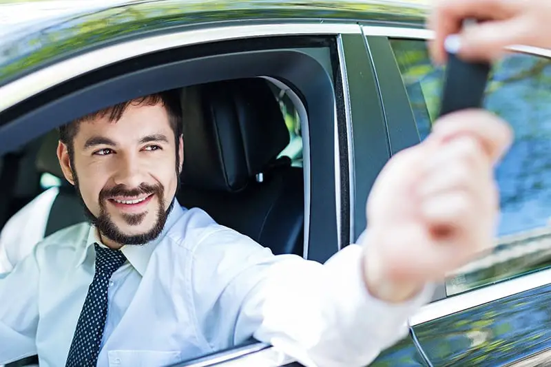 Carsharing - someone handing over keys to man in car