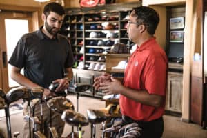 Man standing beside man holding golf club