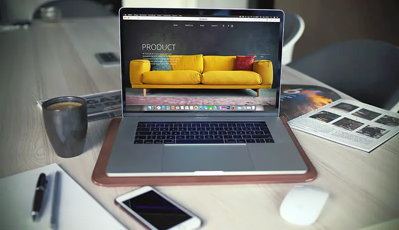 ecommerce online store shown on open MacBook Pro beside a gray mug