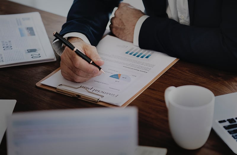 Person holding black twist pen reviewing financial plan