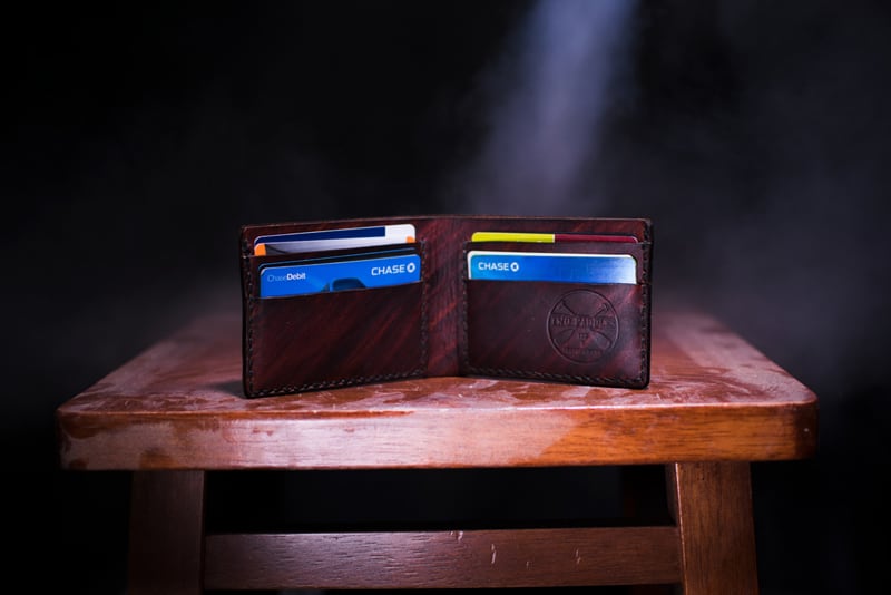 brown leather bifold wallet on table containing credit cards