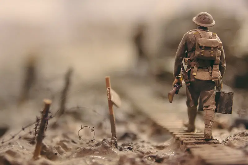 soldier walking on wooden pathway surrounded with barbwire selective focus photography - warfare