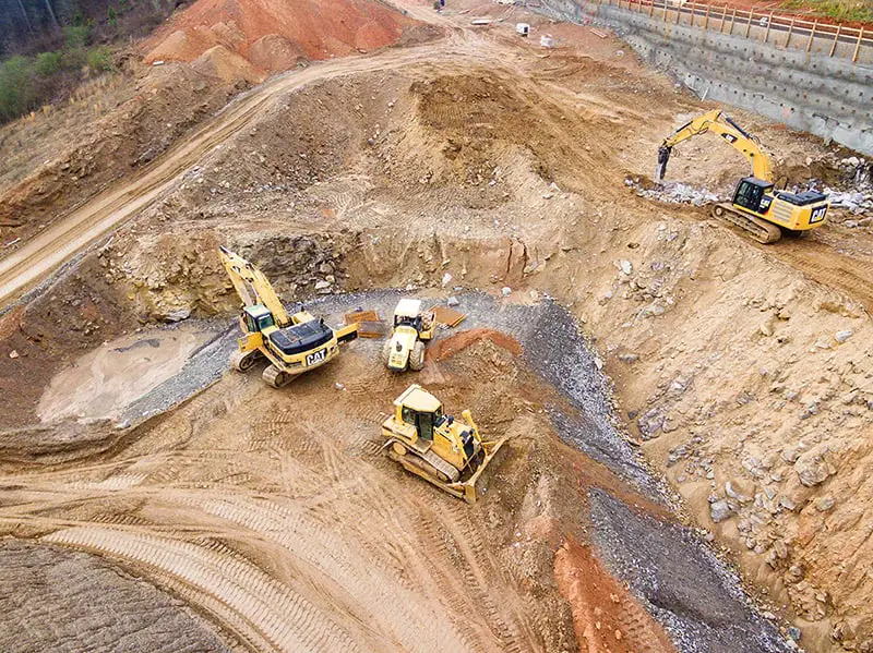 top view photography of four heavy equipment on quarry at daytime 