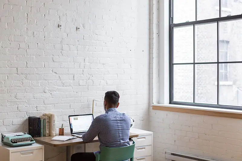 Solo entrepreneur sitting down using his laptop