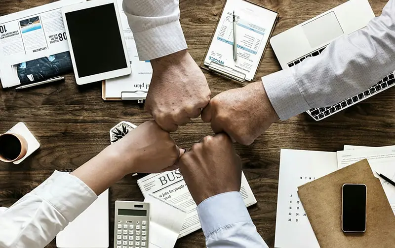 Fist bumps over desk - office management