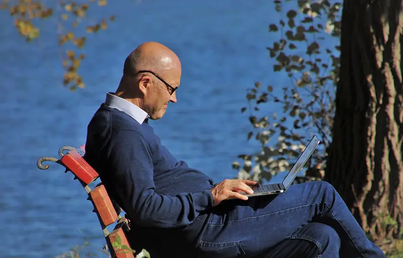 person on bench using pension calculator on laptop