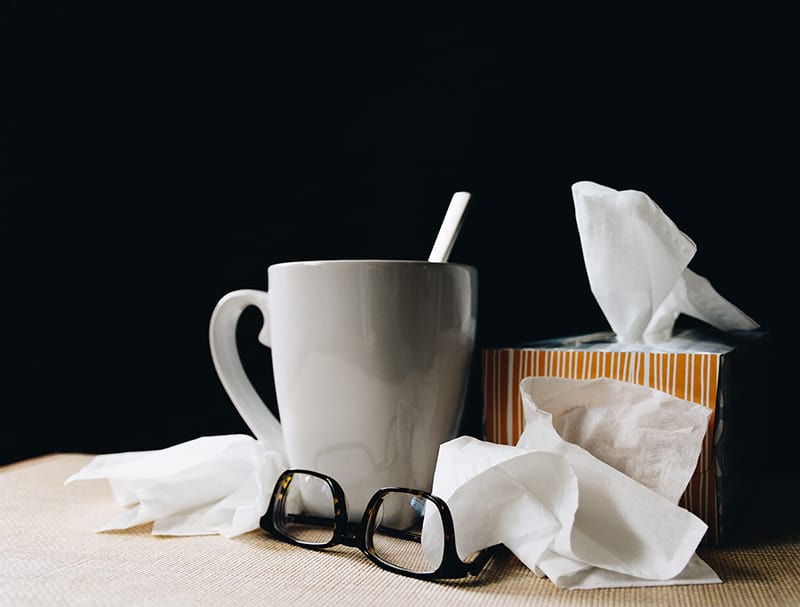 ceraminc mug next to tissues and glassess - health and wellbeing