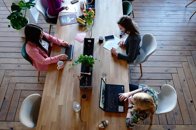 4 women sat a table in a shared office space