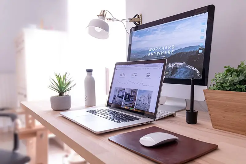 MacBook Pro on table beside white iMac and Magic Mouse showing SEO results