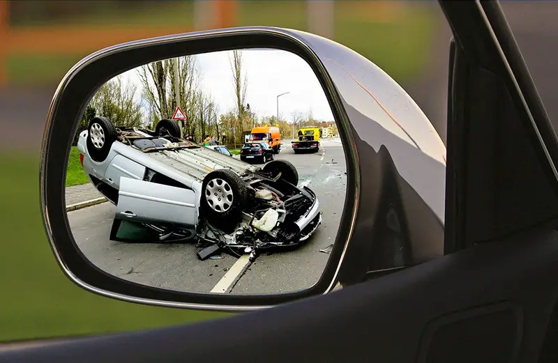 overturned vehicle due to road accident seen in car wing mirror