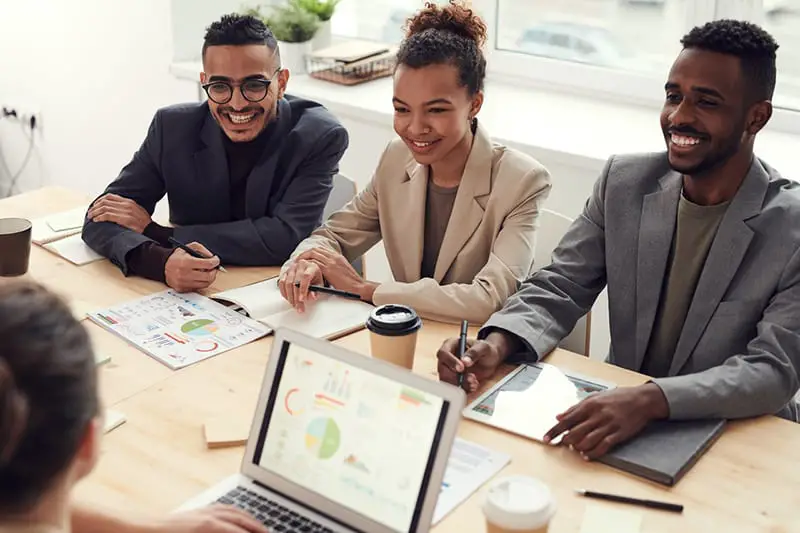 happy employees sitting around a desk for a team meeting