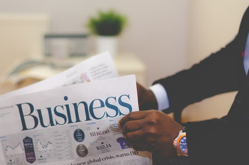 person reading financial pages in business newspaper