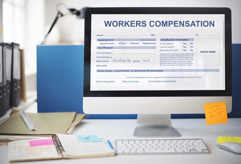 Computer monitor on desk with workers comp information on it